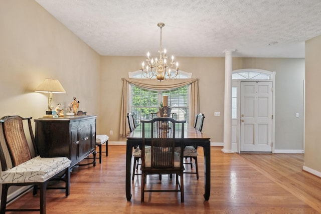 dining room featuring baseboards, a textured ceiling, a notable chandelier, and wood finished floors