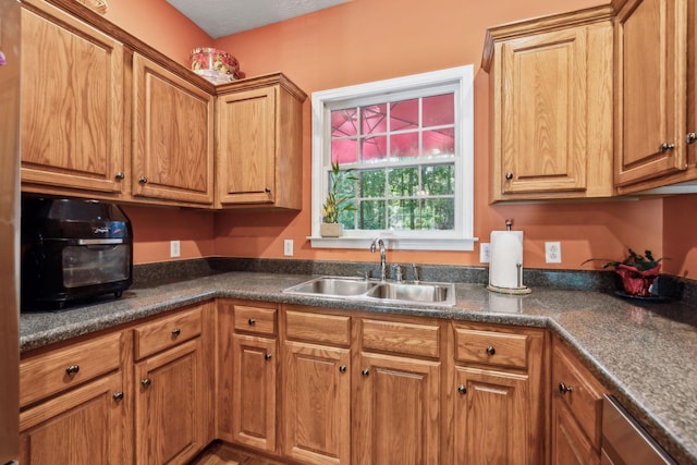 kitchen with a sink, brown cabinets, and dark countertops