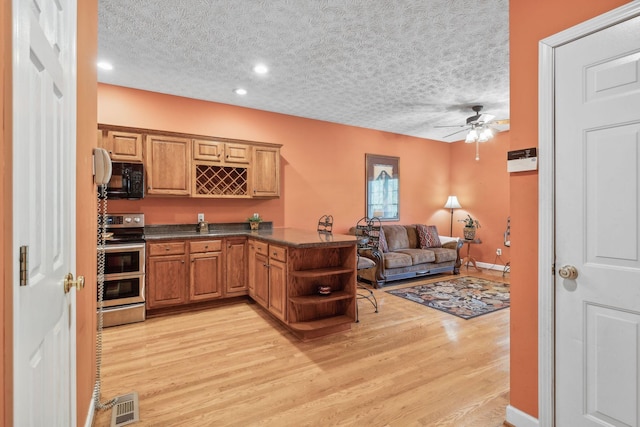 kitchen with dark countertops, black microwave, a textured ceiling, range with two ovens, and light wood-type flooring