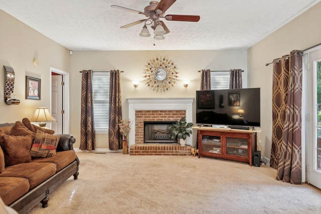 living area featuring carpet flooring, a textured ceiling, a brick fireplace, and ceiling fan