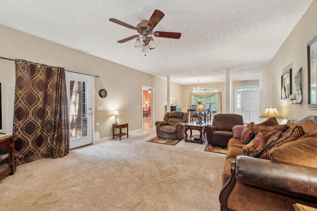 carpeted living room featuring a textured ceiling, baseboards, and ceiling fan with notable chandelier