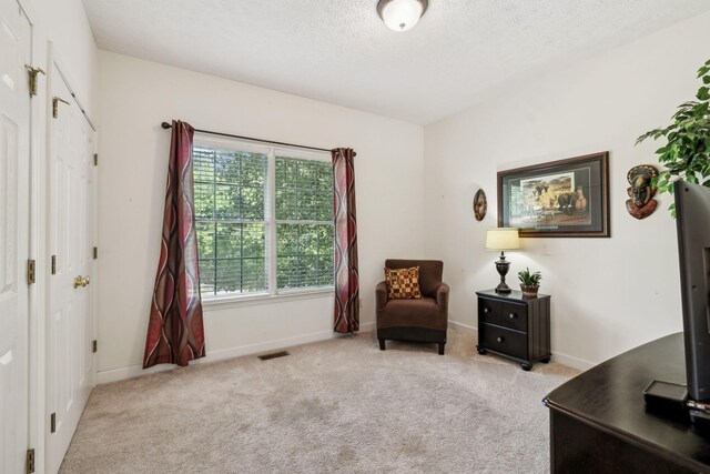 living area with baseboards, carpet, a textured ceiling, and visible vents