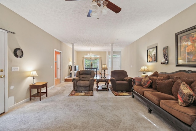 living room with ceiling fan, a textured ceiling, baseboards, carpet flooring, and ornate columns