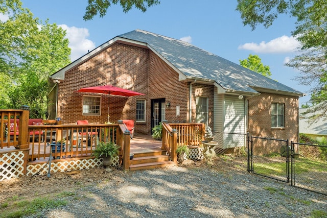 back of house featuring brick siding, fence, a wooden deck, and a gate