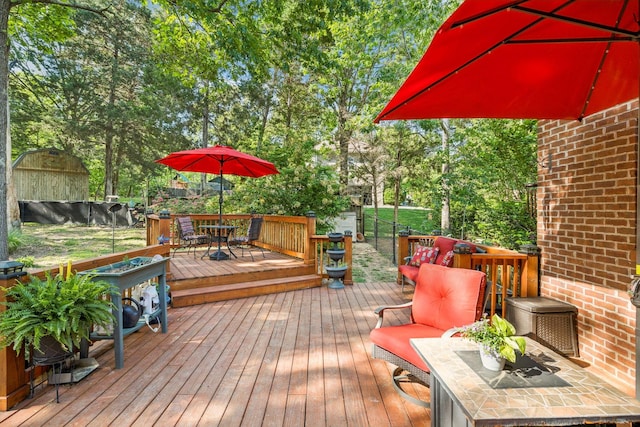 wooden terrace with an outbuilding, outdoor dining area, and a shed
