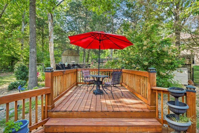 wooden deck featuring a storage unit and outdoor dining space