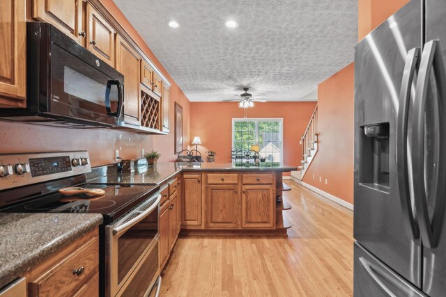 kitchen featuring brown cabinets, stainless steel appliances, and a peninsula