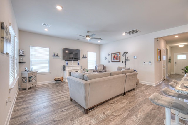 living room with baseboards, a ceiling fan, light wood-type flooring, and visible vents