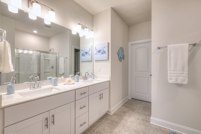 full bath with a sink, baseboards, a shower stall, and double vanity
