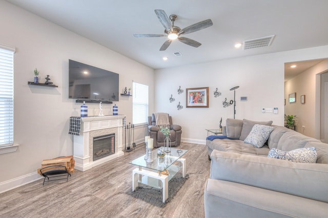 living area featuring visible vents, a ceiling fan, baseboards, and wood finished floors