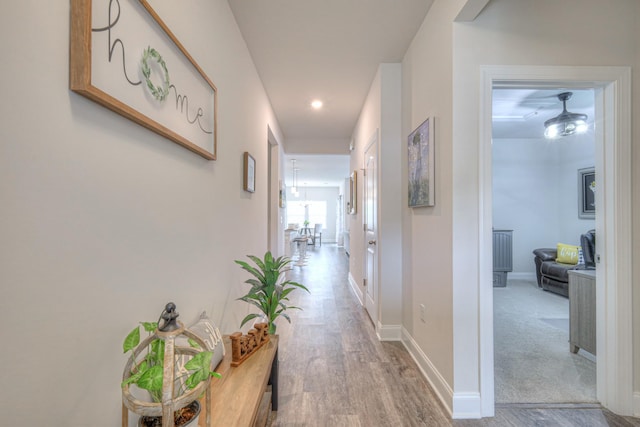 corridor with baseboards, recessed lighting, and wood finished floors