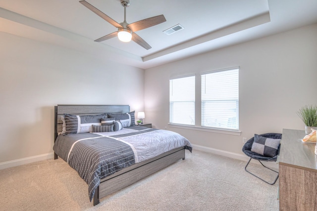 bedroom with visible vents, baseboards, carpet floors, and a tray ceiling
