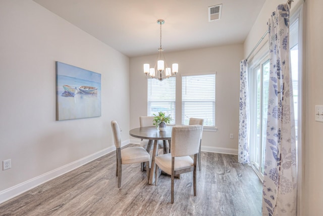 dining area featuring a chandelier, baseboards, visible vents, and wood finished floors