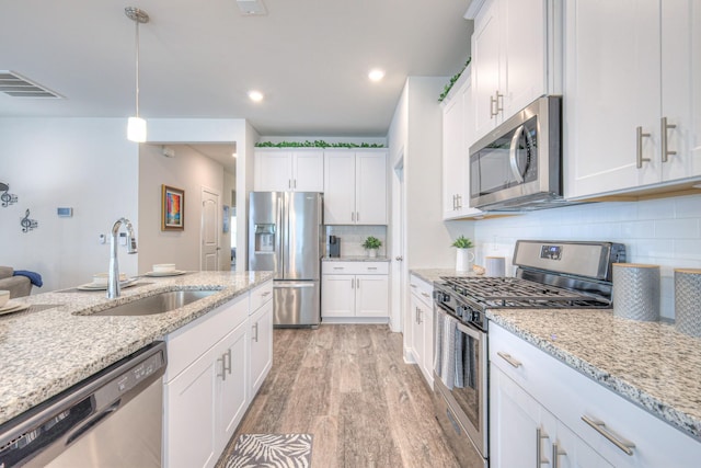 kitchen with a sink, stainless steel appliances, light wood-type flooring, and white cabinetry