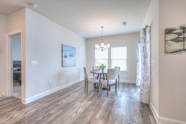 dining area featuring baseboards, a notable chandelier, visible vents, and wood finished floors