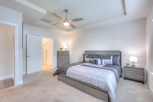 bedroom featuring visible vents, baseboards, ceiling fan, a tray ceiling, and carpet flooring