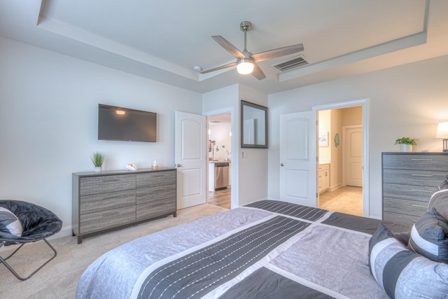 bedroom with ceiling fan, light colored carpet, visible vents, baseboards, and a tray ceiling