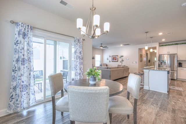 dining room featuring visible vents, ceiling fan with notable chandelier, and light wood-style floors