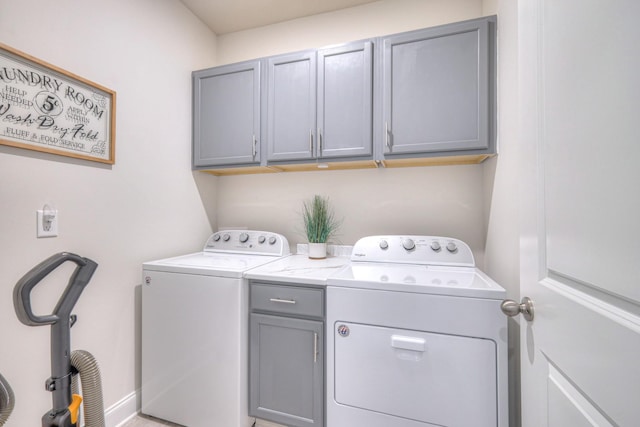clothes washing area featuring cabinet space and washer and clothes dryer