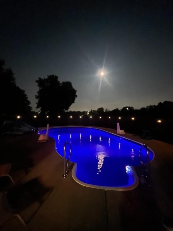 pool at twilight featuring a patio area and an outdoor pool