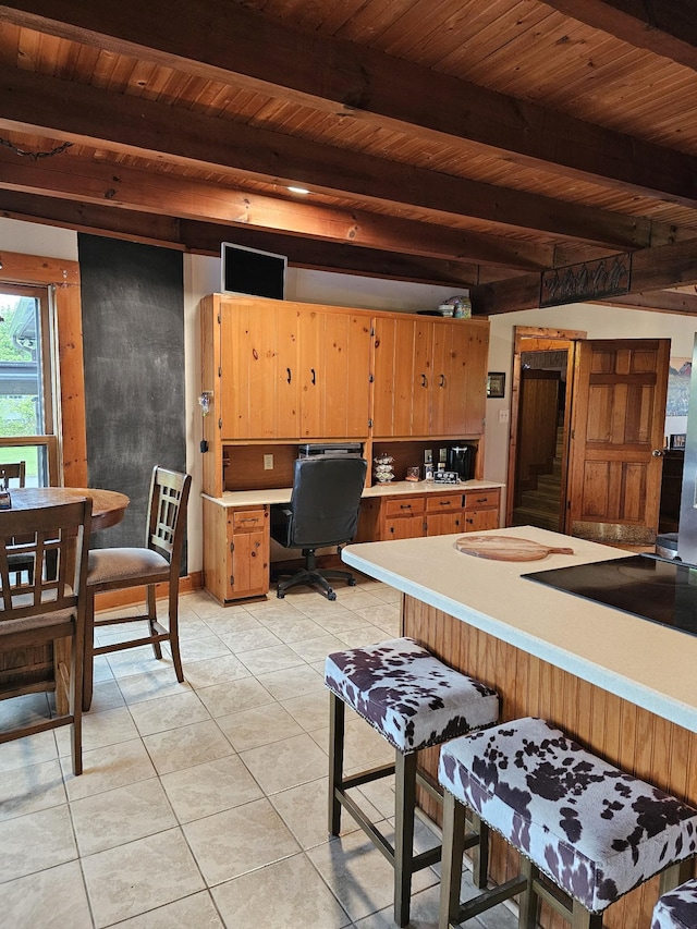 kitchen with light tile patterned floors, beamed ceiling, light countertops, and wood ceiling