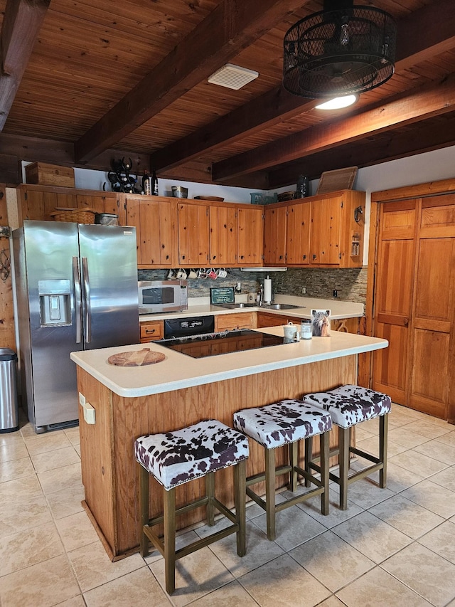 kitchen featuring light tile patterned floors, stainless steel fridge, beamed ceiling, white microwave, and tasteful backsplash