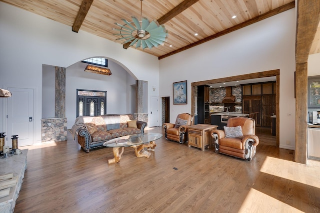living room with a towering ceiling, wood finished floors, wood ceiling, arched walkways, and a ceiling fan