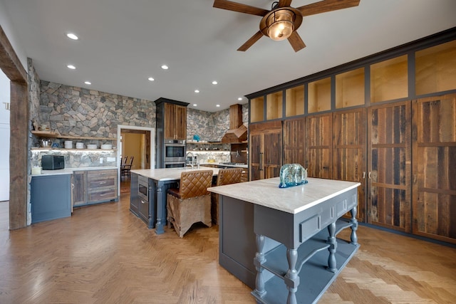 kitchen featuring light countertops, ceiling fan, open shelves, and a spacious island