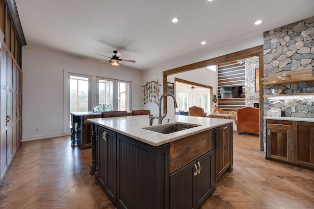 kitchen with a kitchen island with sink, a ceiling fan, plenty of natural light, and a sink