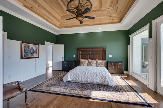 bedroom featuring a high ceiling, a raised ceiling, wood finished floors, ornamental molding, and wood ceiling