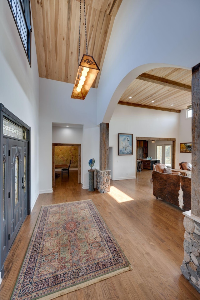 foyer entrance with arched walkways, wood finished floors, wooden ceiling, high vaulted ceiling, and baseboards