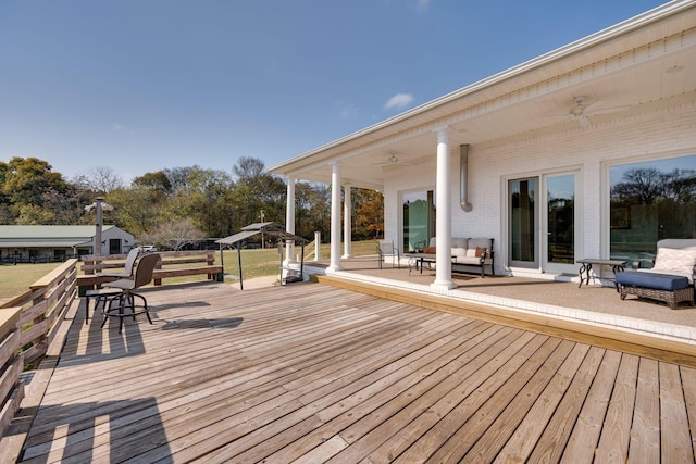 wooden deck with outdoor lounge area and a ceiling fan