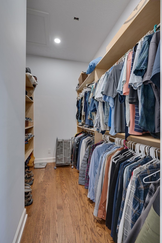 walk in closet featuring attic access and wood finished floors