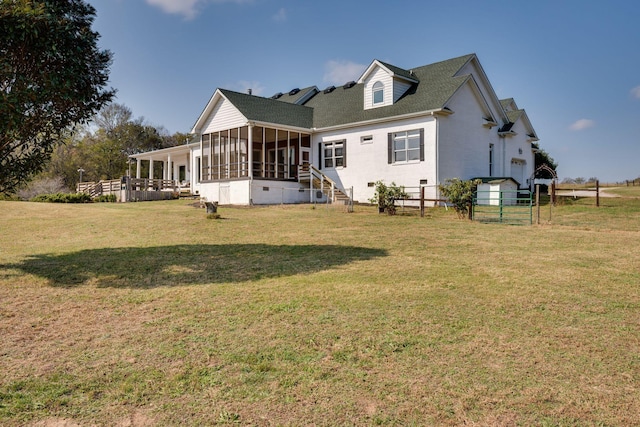 rear view of house with a lawn, fence, and a sunroom