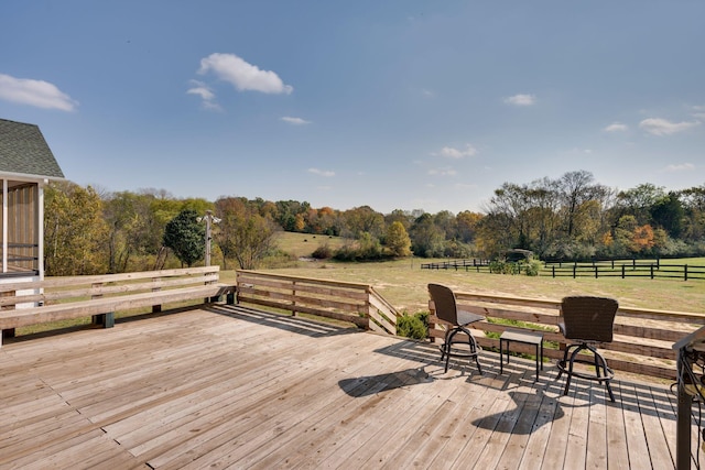 wooden terrace featuring a rural view and fence