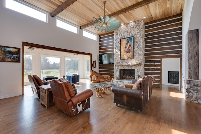 living room with a high ceiling, ceiling fan, a fireplace, wooden ceiling, and wood finished floors