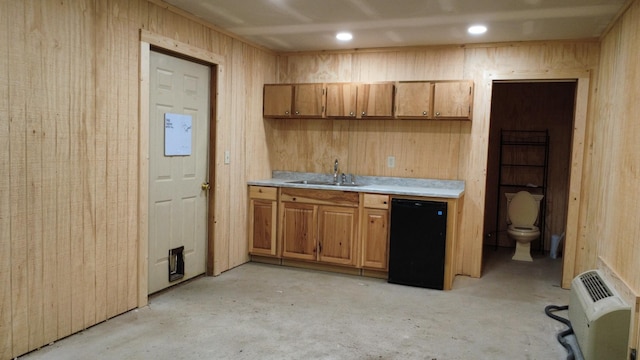 kitchen featuring brown cabinetry, unfinished concrete floors, refrigerator, a sink, and heating unit