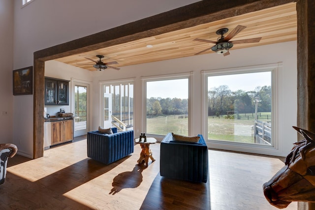 living room with ceiling fan, wood finished floors, and beamed ceiling