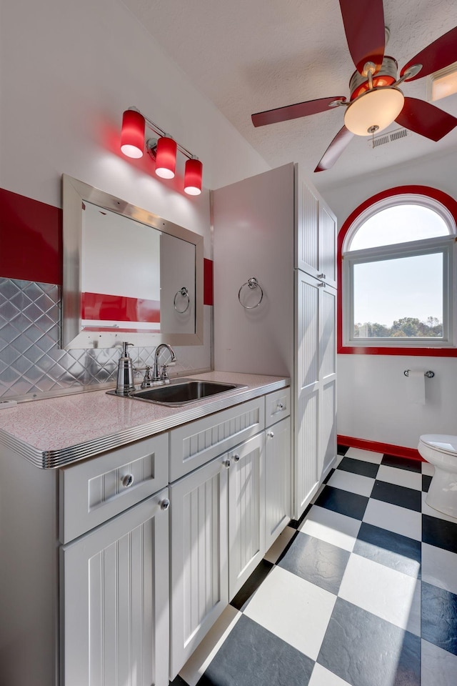 bathroom with visible vents, vanity, toilet, tile patterned floors, and a ceiling fan