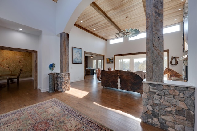 foyer entrance with decorative columns, a towering ceiling, wood finished floors, baseboards, and wood ceiling