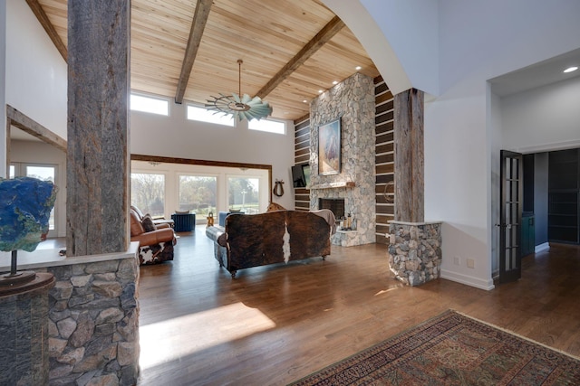 living area featuring a high ceiling, beam ceiling, a fireplace, wood finished floors, and wood ceiling