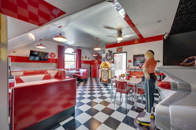 interior space with a textured ceiling, ceiling fan, tile patterned floors, and lofted ceiling