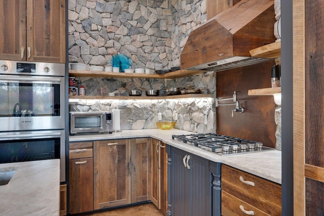 kitchen featuring appliances with stainless steel finishes, open shelves, a toaster, light countertops, and ventilation hood