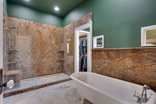 full bathroom with a walk in shower, a freestanding bath, marble finish floor, tile walls, and a spacious closet