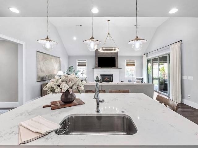 2025 Hornsby Dr, Franklin, TN 37064 - kitchen with a large fireplace, light stone countertops, a center island with sink, a sink, and baseboards