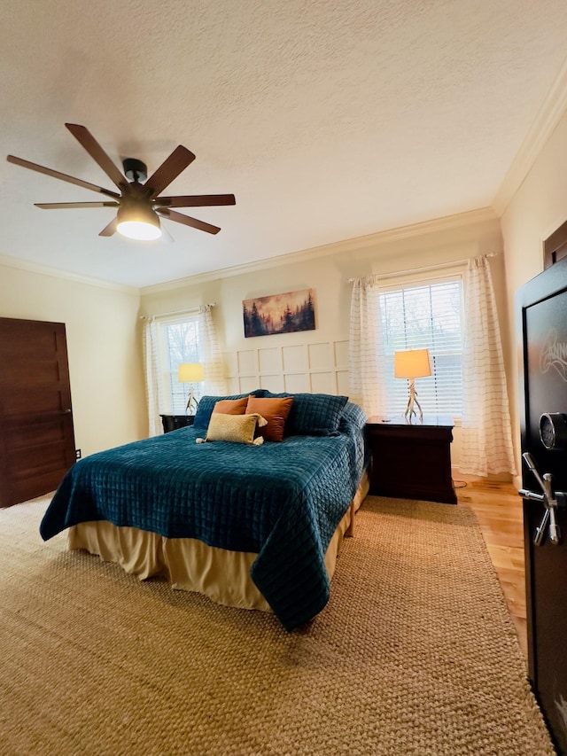 bedroom featuring ceiling fan, light wood-style flooring, crown molding, and a textured ceiling