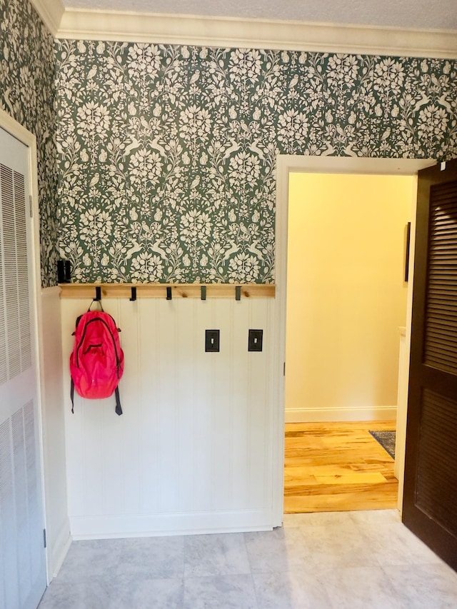 mudroom with wallpapered walls, baseboards, a wainscoted wall, and crown molding