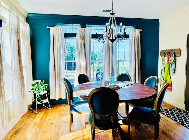 dining space with ornamental molding, a wealth of natural light, a notable chandelier, and light wood-type flooring