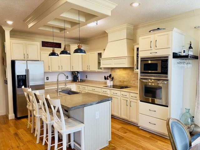 kitchen with backsplash, light wood-style floors, stainless steel appliances, and a sink