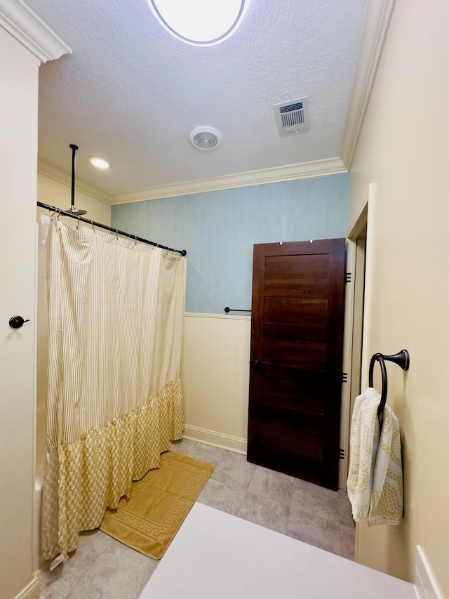 bathroom featuring a textured ceiling, visible vents, and ornamental molding